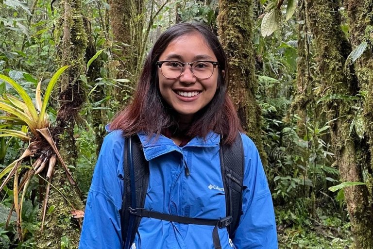 Chanchanok wears a blue windbreaker and backpack while in a jungle in Thailand