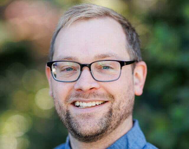 Man in blue shirt wearing glasses.
