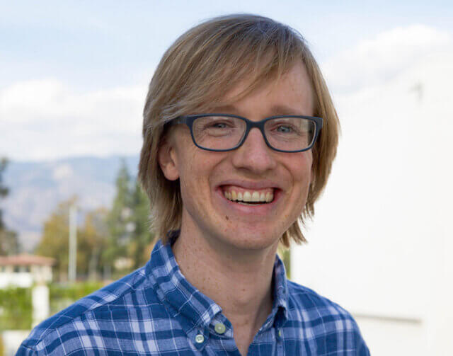 Man in stripped blue and white shirt with glasses.