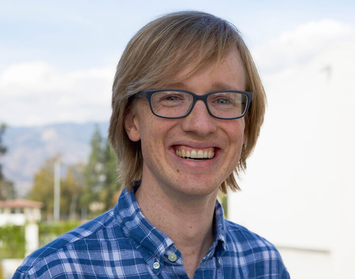 Man in stripped blue and white shirt with glasses.