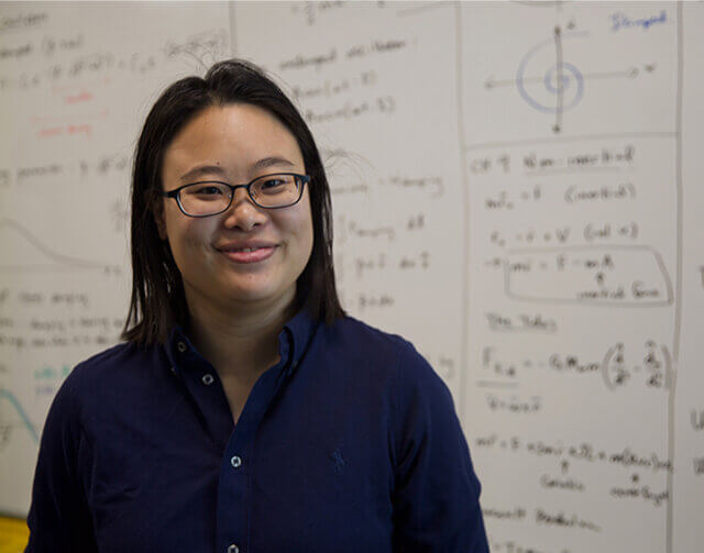 Woman with black short hair and glasses with black button up blouse.