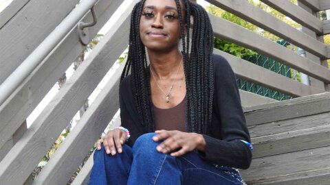 a student with braids sites on a staircase