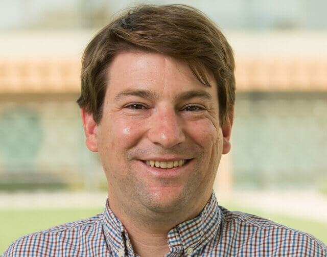 Man with striped shirt and short light brown hair.