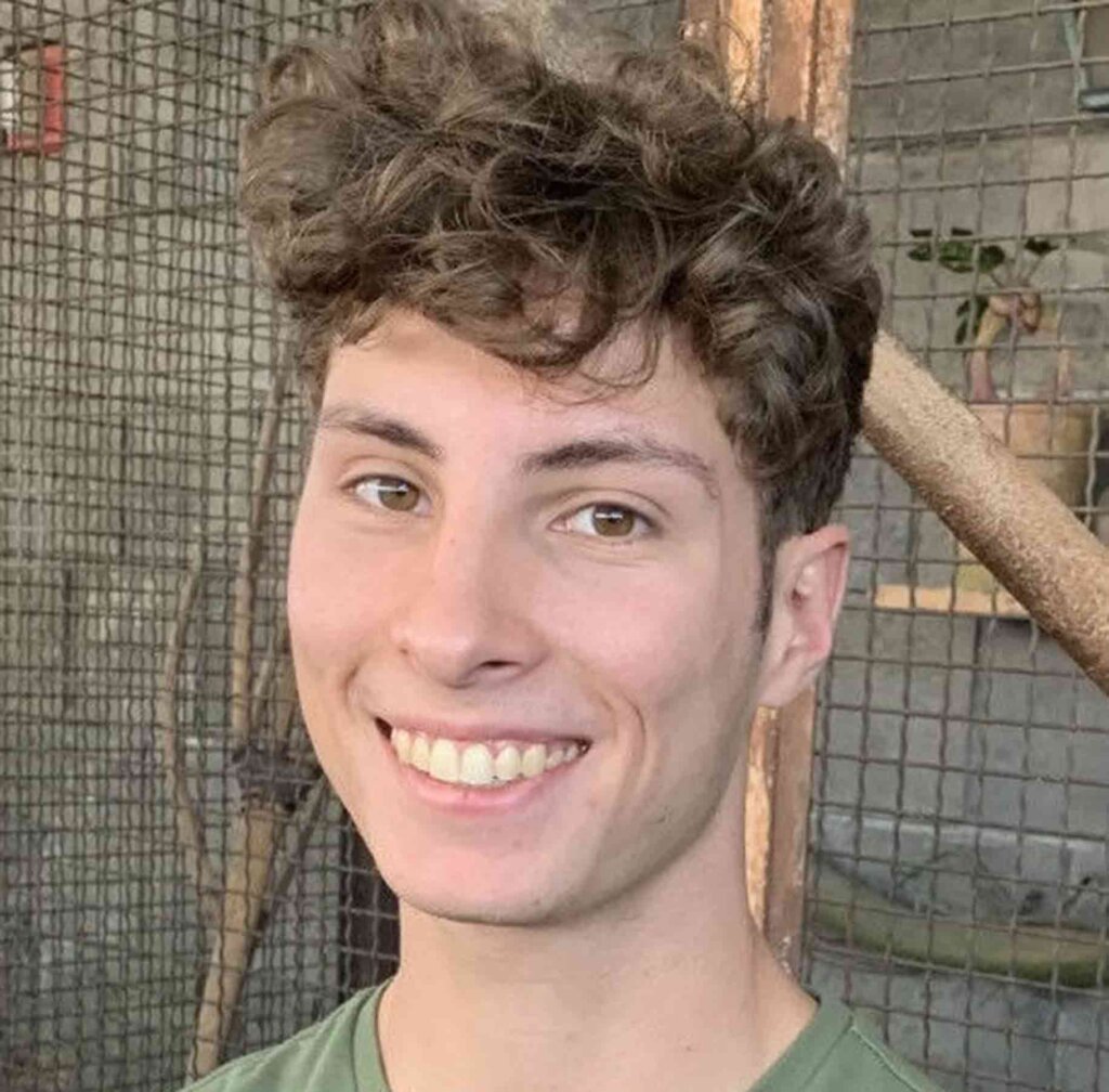a man with short brown curly hair smiles at the camera