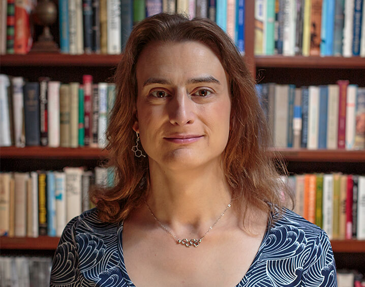 Woman with short light brown hair and blue long sleeve blouse.