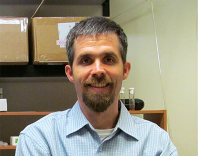 Man with short black hair and light blue button up.