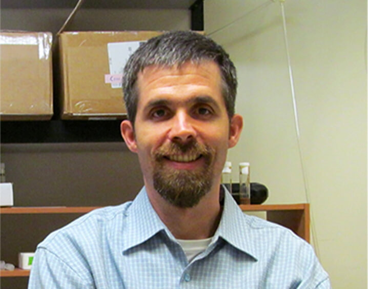 Man with short black hair and light blue button up.