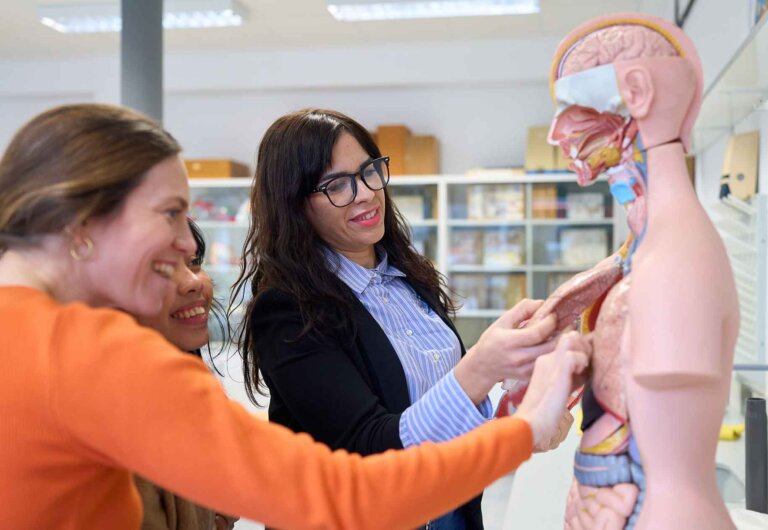 three students interact with an anatomical model of a human