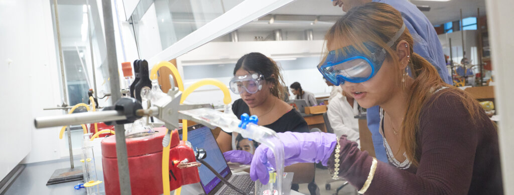 Two students work under a fume hood