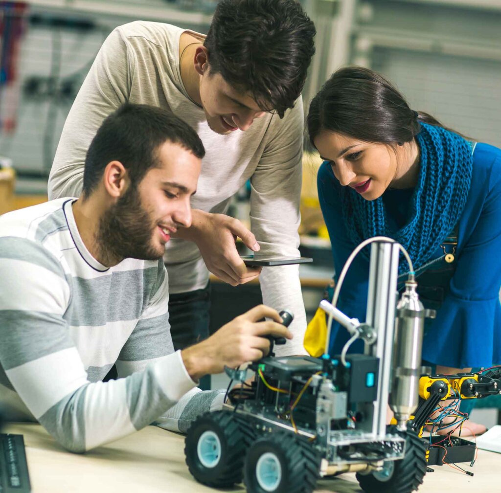 three students work on a remote control car model