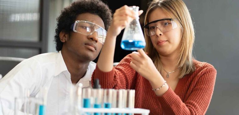 two grad students observe liquid in a vial