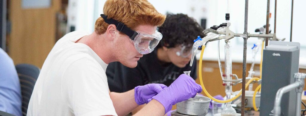 two student work on a chemistry experiment together in a lab