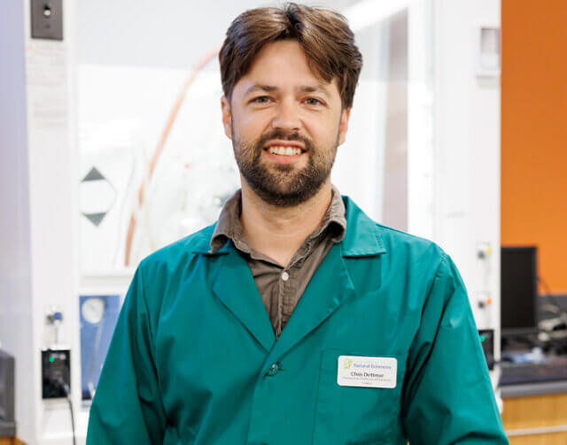 Man in brown shirt and turquoise lab coat.