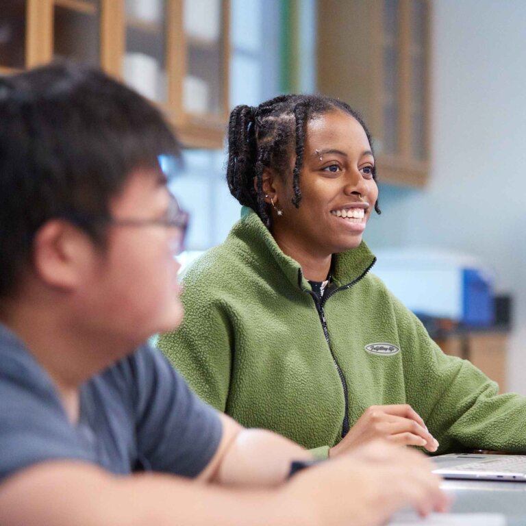 two students sit at a desk in a classroom