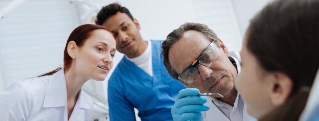 Students watch as a dentist performs an oral exam