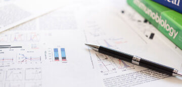 a black pen sits on top of printed report pages with graphs