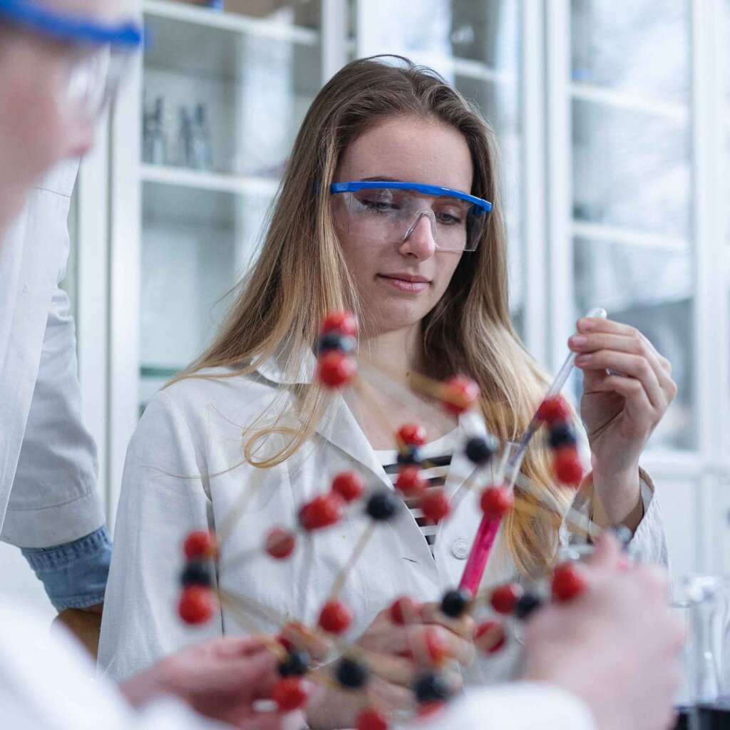 a student wears protective eyewear while add liquid to a vial with a dropper.