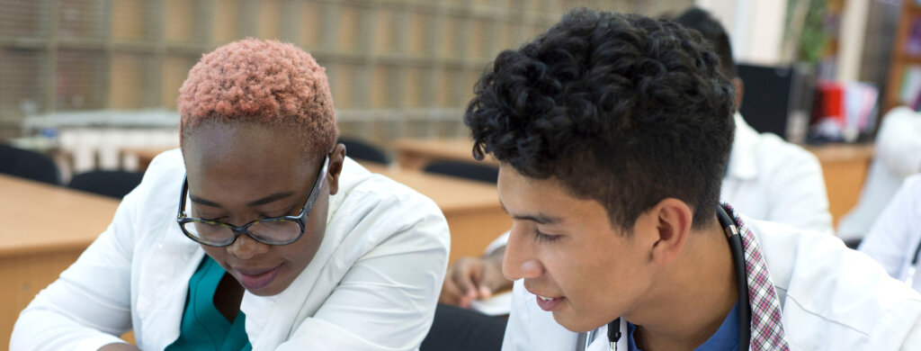 Two medical students look at their notes during a lecture