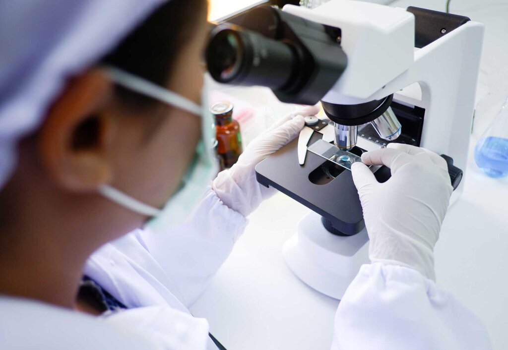 a lab technician prepares a slide on a microscope base.