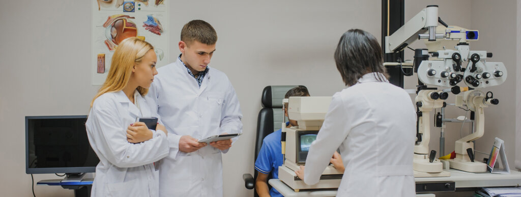 Students look on as an optometrist performs an eye exam