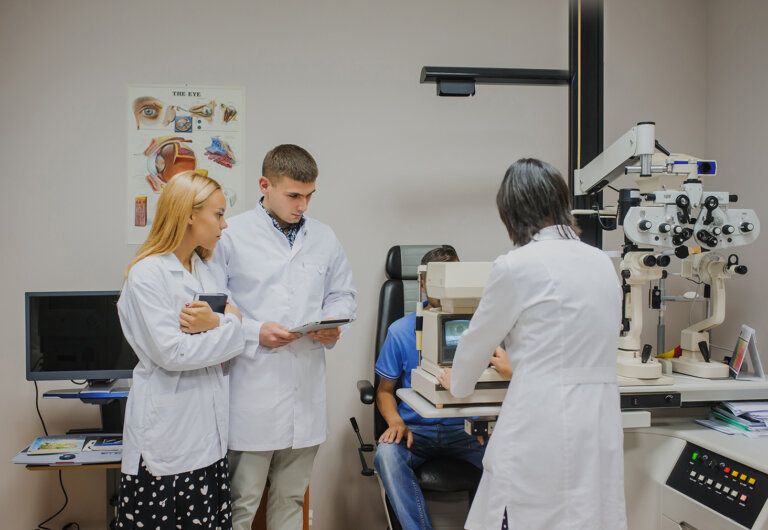 Students look on as an optometrist performs an eye exam