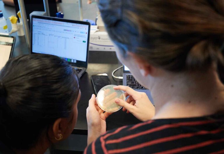 two students study a petri dish up close