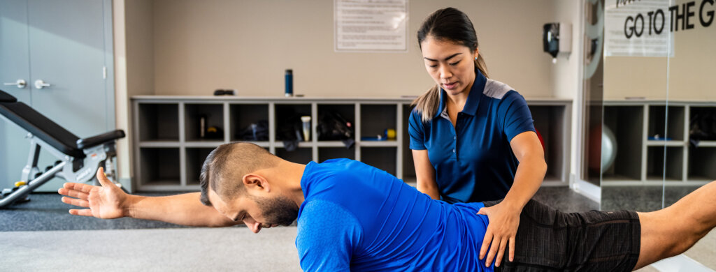 A physical therapist guides a patient in performing an exercise