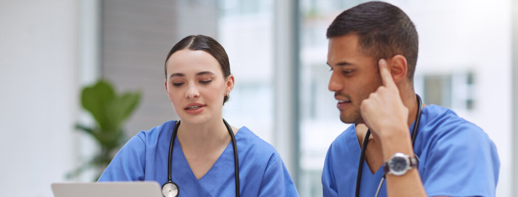 Two physician assistants work on a laptop