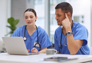 Two physician assistants work on a laptop