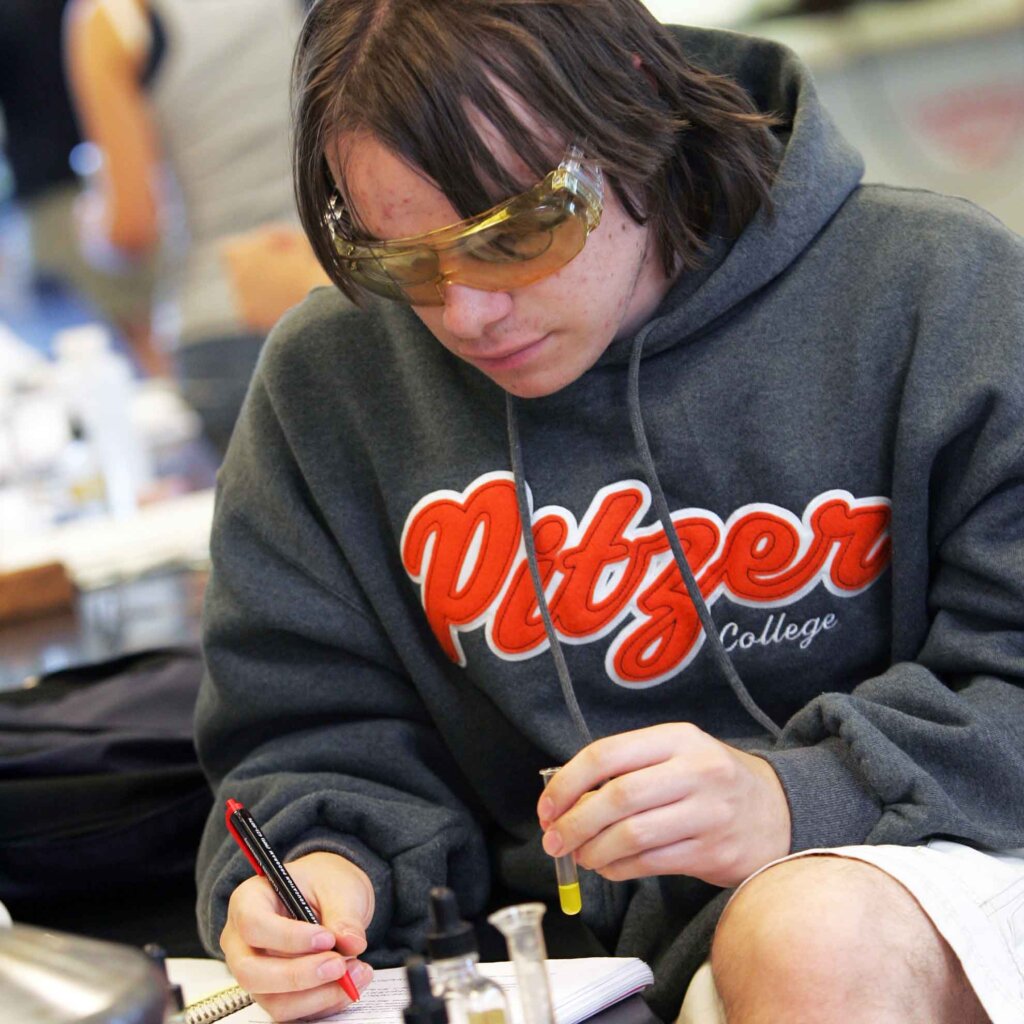 a student wearing a pitzer sweatshirt works with chemicals in vials