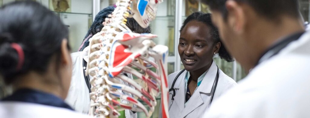 four student stand around a model of a human skeleton