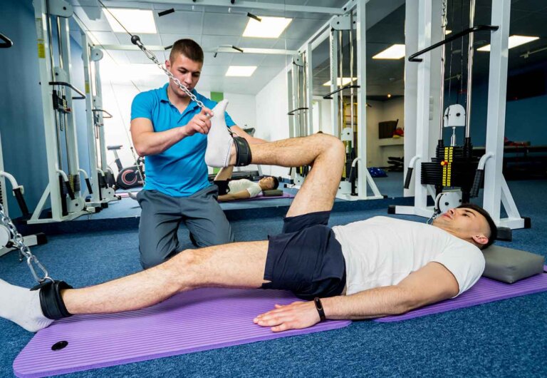 a physical therapist supervises a patient doing leg weight exercises