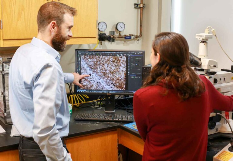 a professor and student collaborate at a computer station