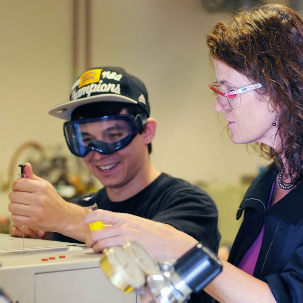a student works with a syringe with a professor watching