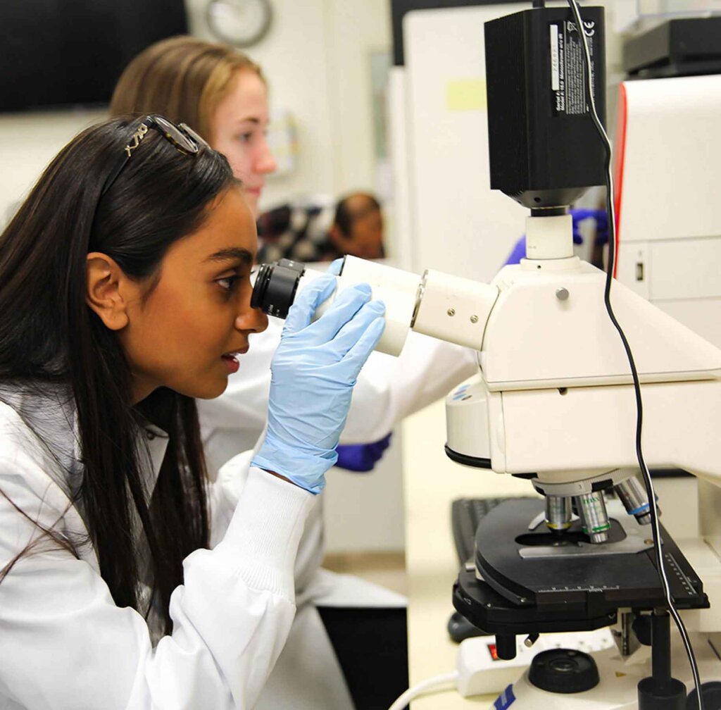 a woman peers into a micrscope in a lab