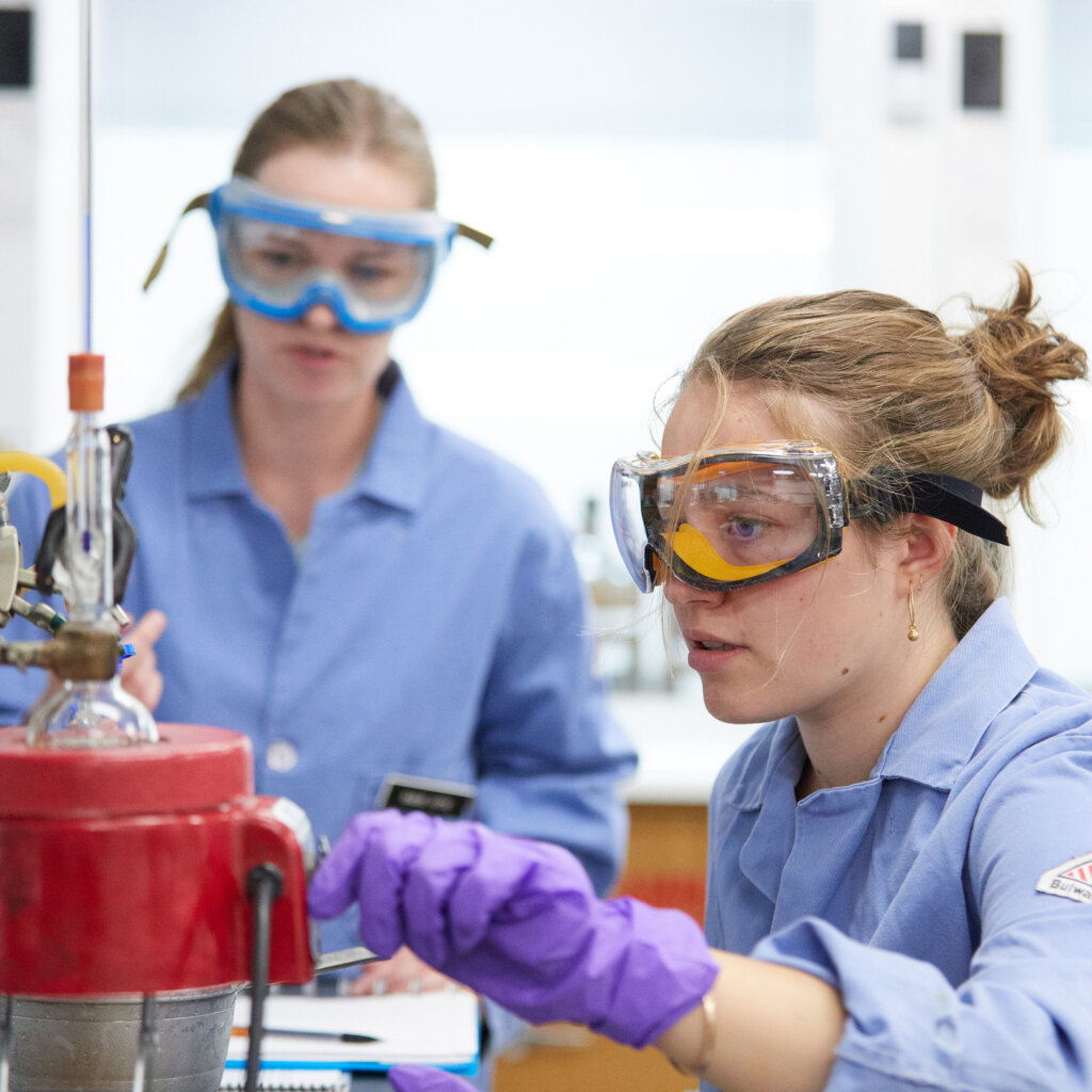 Two students watch a flask on a heating mantle