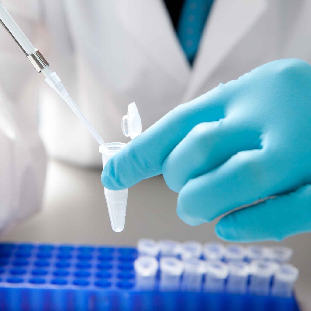 a lab tech drops liquid into a vial