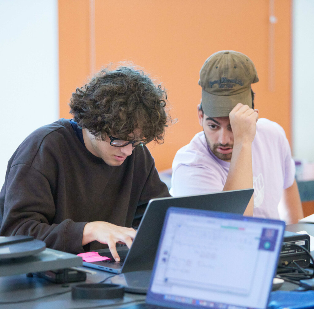 Two students work on a laptop in a physics lab