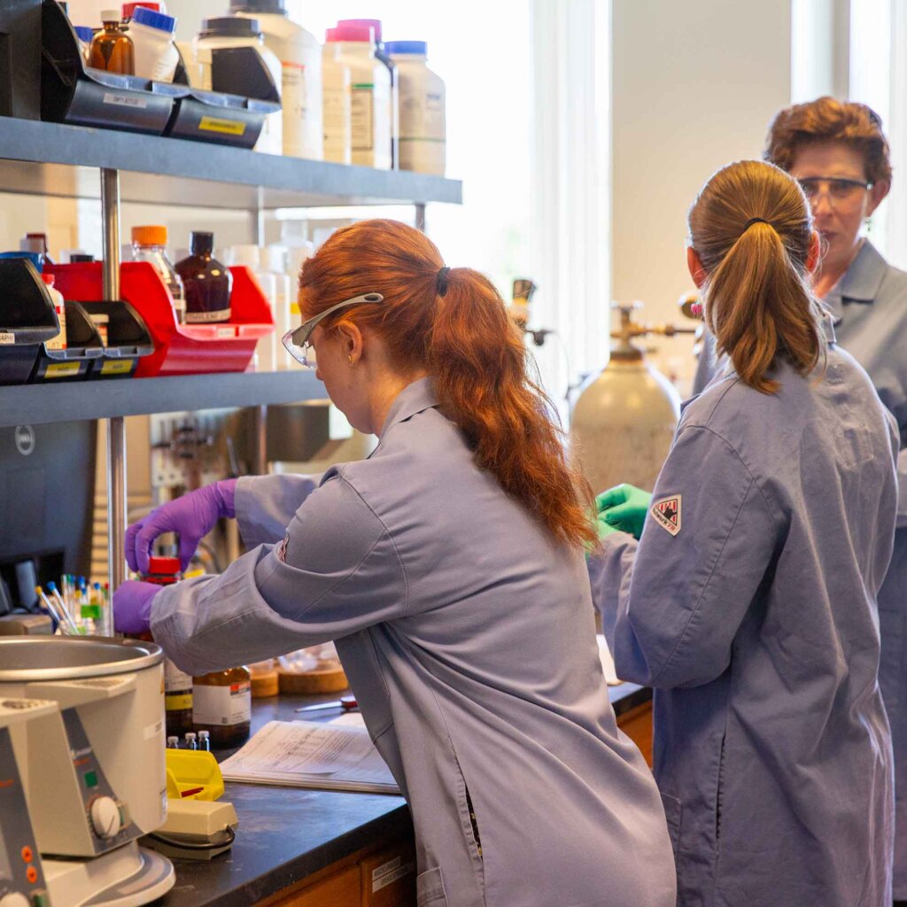 two student work in a lab with professor wenzel