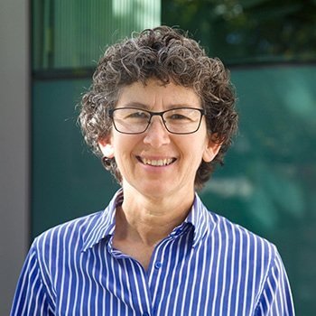 portrait of a woman with short brown h air, black glasses wearing a blue and white striped collared shirt.