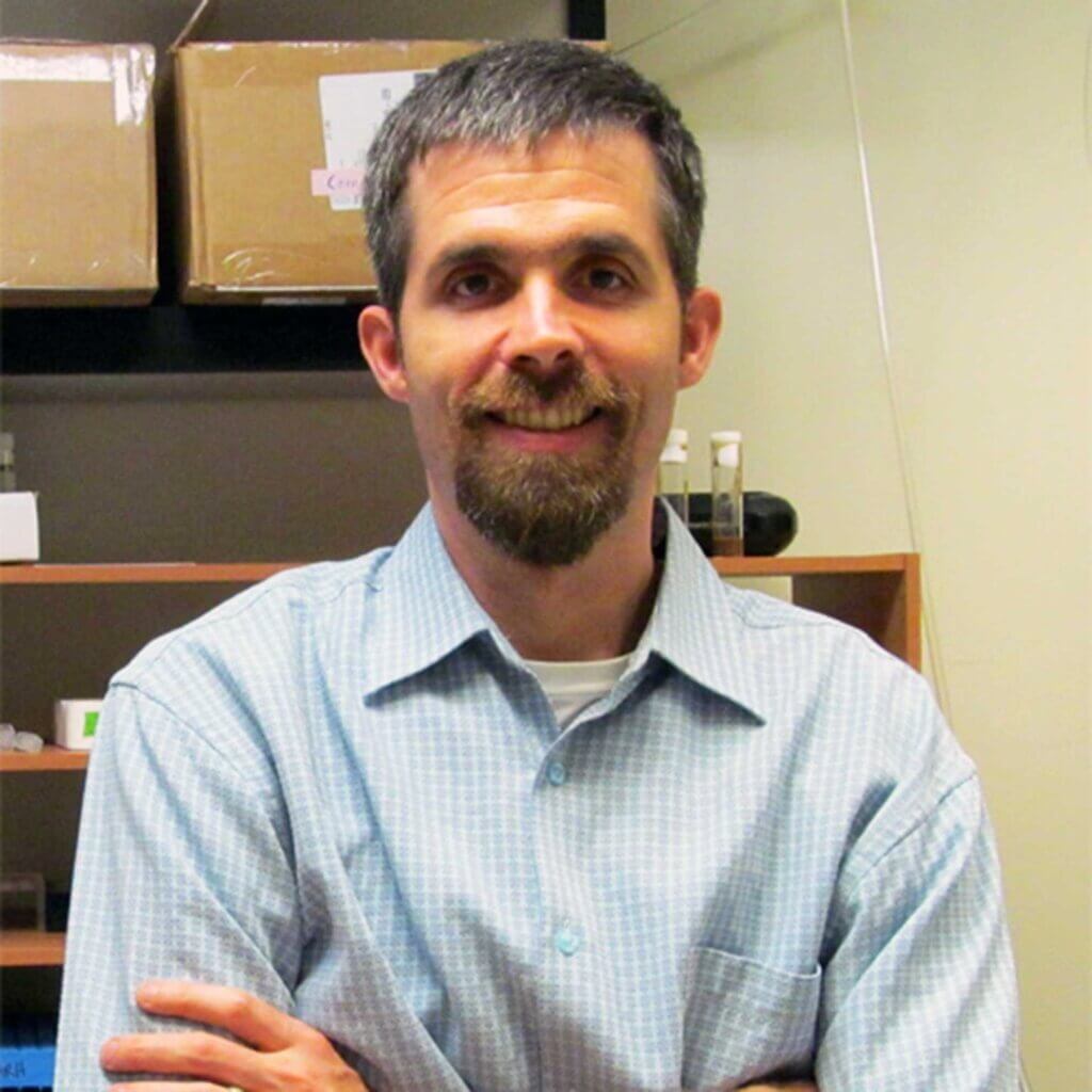 patrick feree stands with this arms crossed in a lab