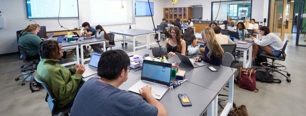 biology class tudents sit at desks with their laptops