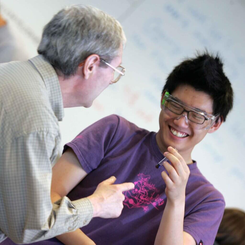 a professor guides a student holding a test tube.
